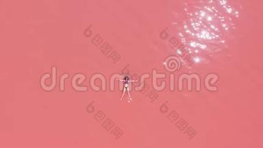空中观景。 一个美丽的年轻女孩躺在粉红色的湖里，一件比基尼，太阳镜，粉红色的<strong>清澈</strong>的水，一张最高的<strong>风</strong>景。